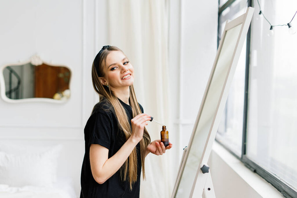 Beautiful lady doing make up and hair in bedroom. Attractive young female with pretty long hair - Fotoğraf, Görsel