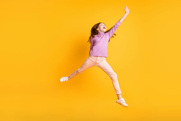 Full size photo of young funky excited cheerful crazy little girl jumping look copyspace isolated on yellow color background - Φωτογραφία, εικόνα