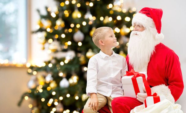 smiling boy with santa claus and gifts at home - Fotó, kép