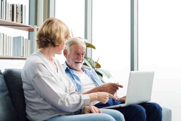 Vanhempi vanhempi perhe pari istuu modernissa olohuoneessa yhdessä kannettavan tietokoneen avulla. Vanha mies hämmentyä modernin teknologian. - Valokuva, kuva