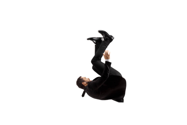 Man in a black suit falling on the ground isolated on white background - Fotografie, Obrázek