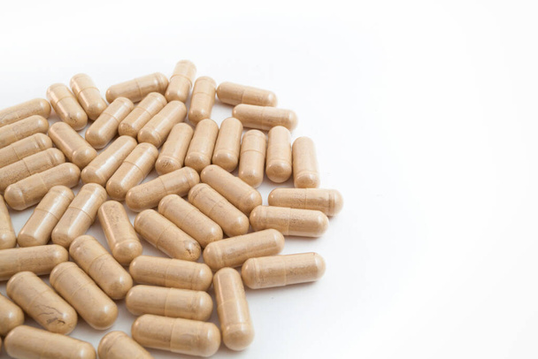 Bruine capsule pillen op witte geïsoleerde achtergrond - Foto, afbeelding