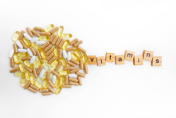 vitaminas de inscripción en cubos de madera sobre un fondo blanco de diferentes píldoras - Foto, imagen