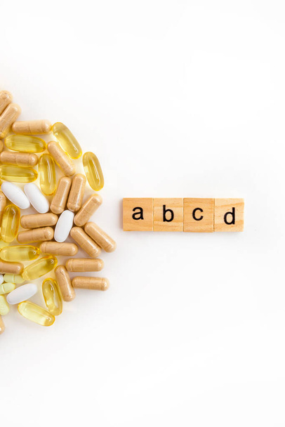 napis B C E w drewnianych kostkach na białym tle różnych tabletek - Zdjęcie, obraz