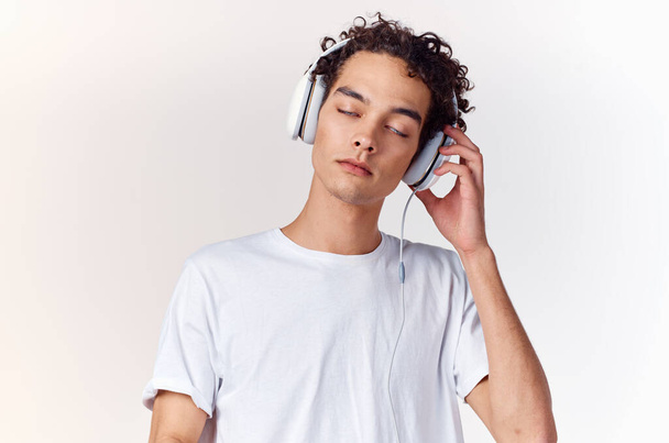 cara de cabelos encaracolados em t-shirt branca com fones de ouvido  - Foto, Imagem
