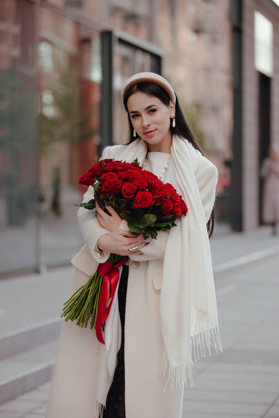 Happy woman holding bouquet of roses flowers in the city - Fotografie, Obrázek