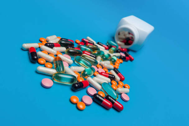 разноцветные таблетки, падающие из банки на голубом фоне - Фото, изображение