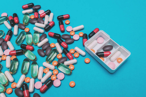 Tablettenspender mit bunten Pillen auf blauem Hintergrund - Foto, Bild