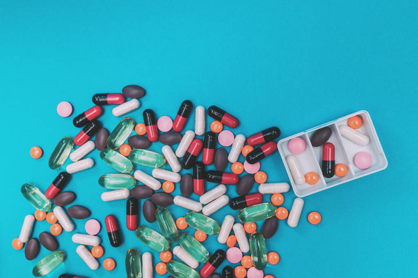 distributeur de pilules avec des pilules multicolores sur fond bleu - Photo, image