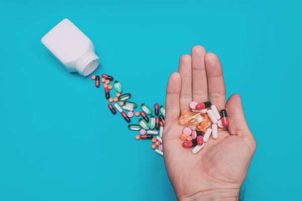 pílulas multicoloridas na mão sobre fundo azul - Foto, Imagem