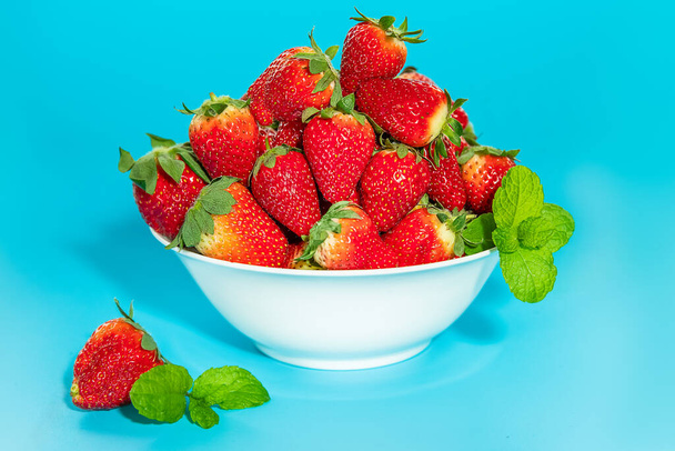 frisch gepflückte Bio-Erdbeere isoliert vor blauem Hintergrund, gesunde Ernährung - Foto, Bild