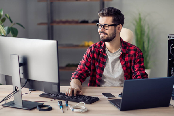 Portrait of attractive skilled qualified cheerful guy engineer programming web development at office work place station indoor. - Фото, изображение