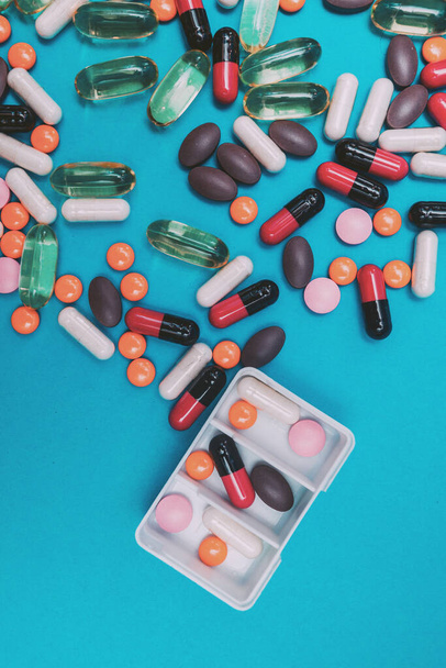dispensador de pastillas con píldoras multicolores sobre fondo azul - Foto, imagen