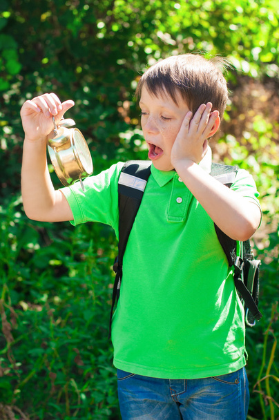 Boy with a backpack and a clock in hands - Foto, Bild