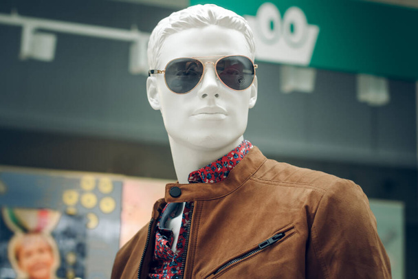 POLAND, BYDGOSZCZ - 11 лютого 2020: Портрет чоловічого манекена в коричневій куртці, сорочці та сонцезахисних окулярах. Білий дурень у чоловічому одязі в магазині. Купівля - Фото, зображення
