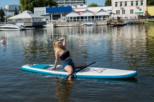 mooi jong europees vrouw met sup boord op water van rivier - Foto, afbeelding