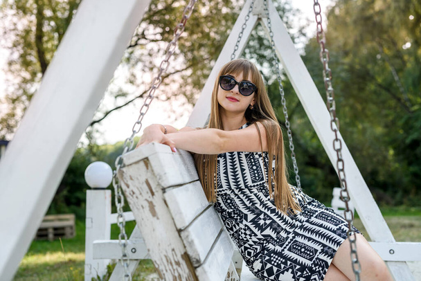 beautiful woman breathing on a white wooden swing in summer - Photo, image