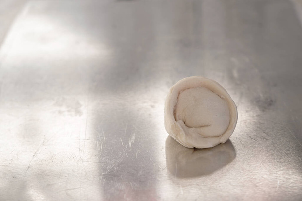 One frozen semi-finished products dumpling or pelmeni on a shiny steel surface. Hand molding. Copy space. - Photo, Image