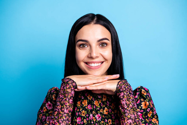 Photo of cute positive lady hands chin beaming shiny smile wear floral print shirt isolated blue color background. - 写真・画像
