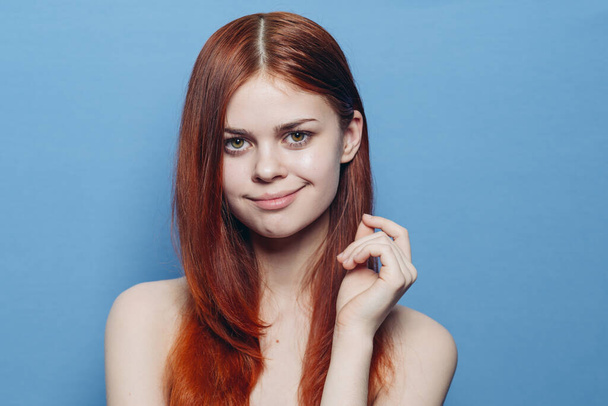 attractive woman with bare shoulders red hair close-up blue background - Foto, immagini