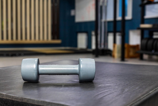 grijze kleine halter op matten. in de trainingsruimte. wazig sportschool achtergrond - Foto, afbeelding