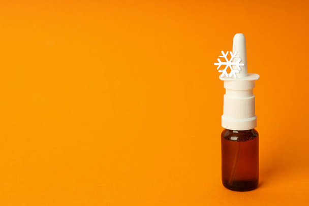 Leere Flasche Nasenspray mit dekorativer Schneeflocke auf orangenem Hintergrund - Foto, Bild