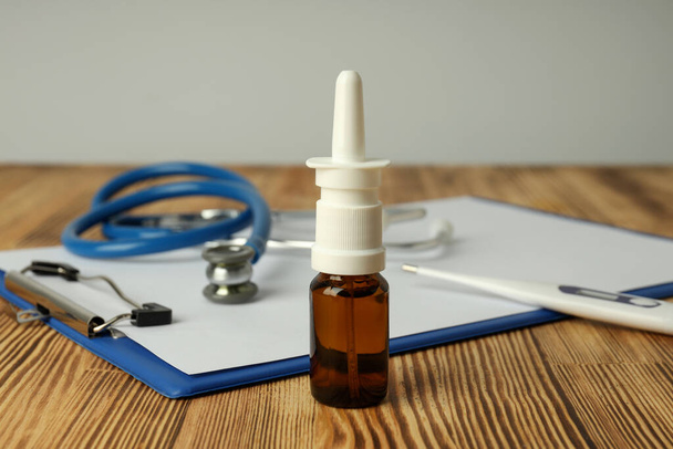 Nasal spray, stethoscope, thermometer and clipboard on wooden table - Zdjęcie, obraz