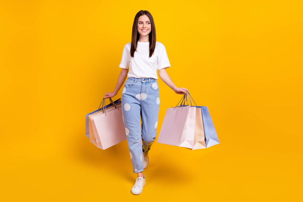 Full size photo of happy good mood smiling positive girl go shopping look copyspace isolated on yellow color background. - Fotó, kép