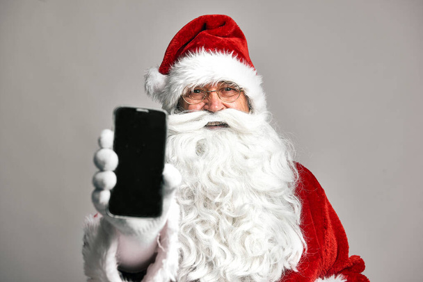 Дед Мороз показывает экран мобильного телефона  - Фото, изображение