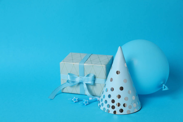 Dárek box, čepice, balón a svíčky na modrém pozadí - Fotografie, Obrázek