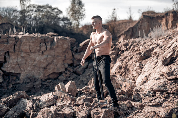 Brutal strong bodybuilder posing outdoor. Photoshoot in a quarry. Outdoor sports concept. Posing and pumping muscles. Nature landscape - Fotó, kép