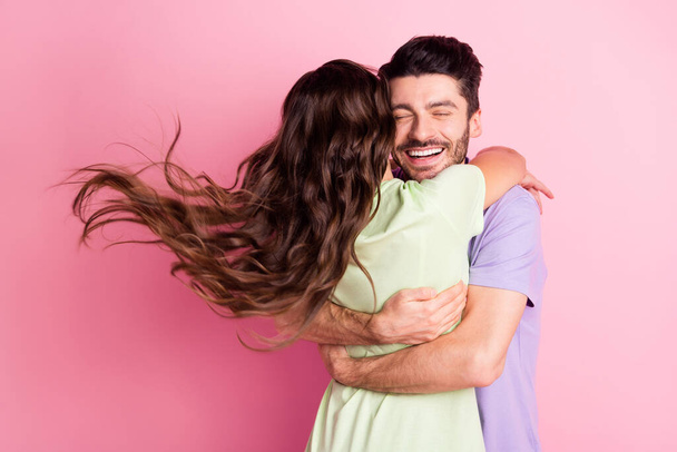 Portrait of attractive dreamy affectionate cheerful couple embracing wind blowing hair isolated over pink pastel color background - Fotografie, Obrázek