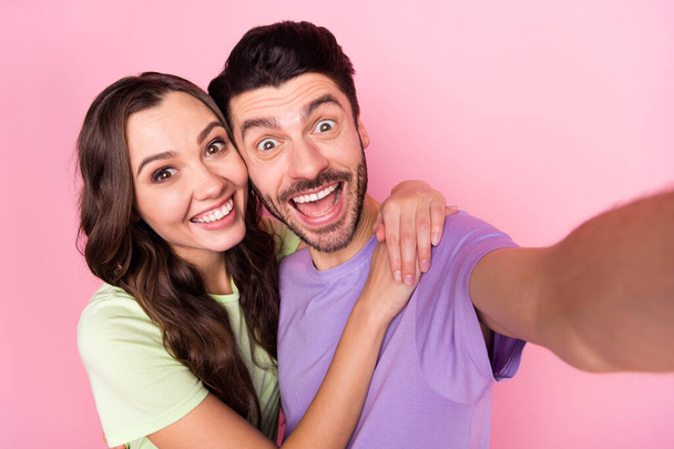 Self-portrait of attractive funky childish amazed cheerful couple embracing having fun isolated over pink pastel color background - Foto, immagini