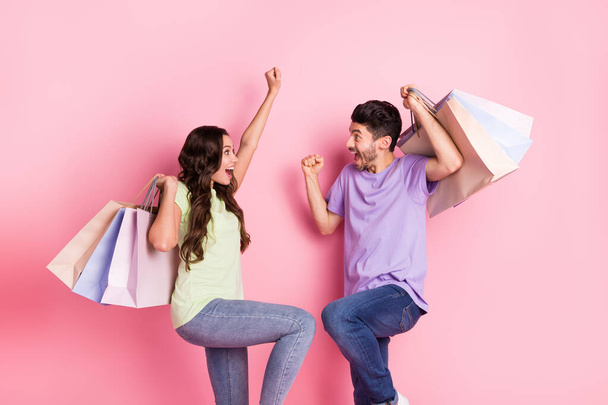 Portrait of attractive lucky trendy cheerful couple carrying news things clothes having fun black friday isolated on pink pastel color background - 写真・画像