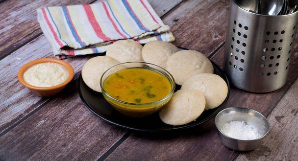 Πιάτο idlis από αλεύρι από κεχρί banyard με κύπελλα sambhar και τσάτνεϊ καρύδας σε ξύλινο τραπέζι. - Φωτογραφία, εικόνα
