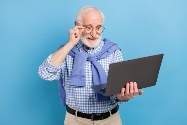 Photo of optimistic old grey hairdo man hold laptop wear spectacles blue shirt isolated on pastel color background - Photo, Image