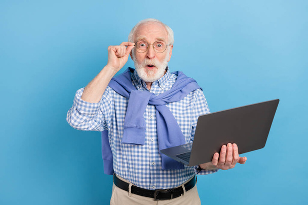 Photo of impressed old grey hairdo man hold laptop wear spectacles blue shirt isolated on pastel color background - Fotografie, Obrázek