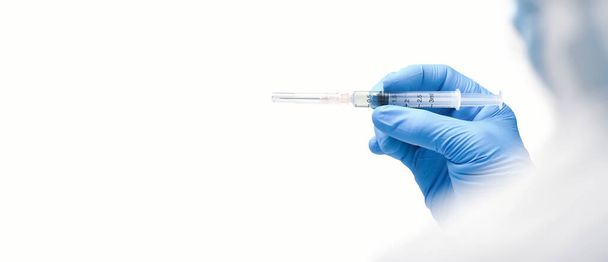 De medische spuit in de hand voor bereide injectie, horizontale kopieerruimte op witte achtergrond - Foto, afbeelding