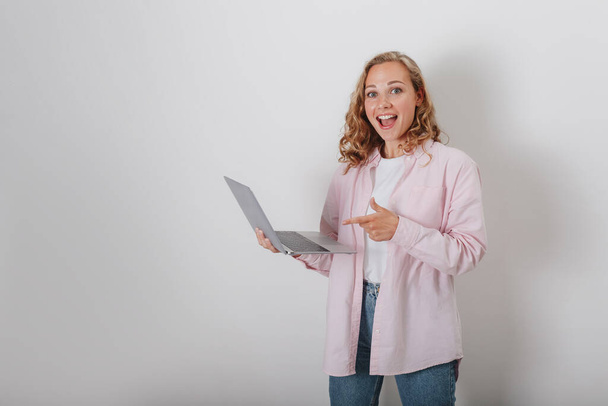 A girl with curly hair on a white background holding a laptop - Fotó, kép