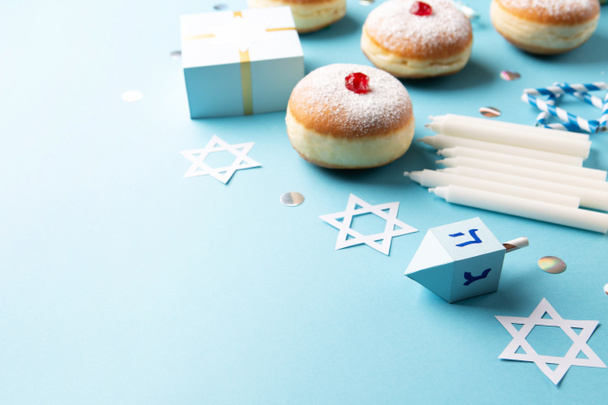 Hanukkah sweet doughnuts sufganiyot with powdered sugar and fruit jam, gift boxes on blue paper background. Jewish holiday Hanukkah concept. Selective focus, copy space - Photo, Image