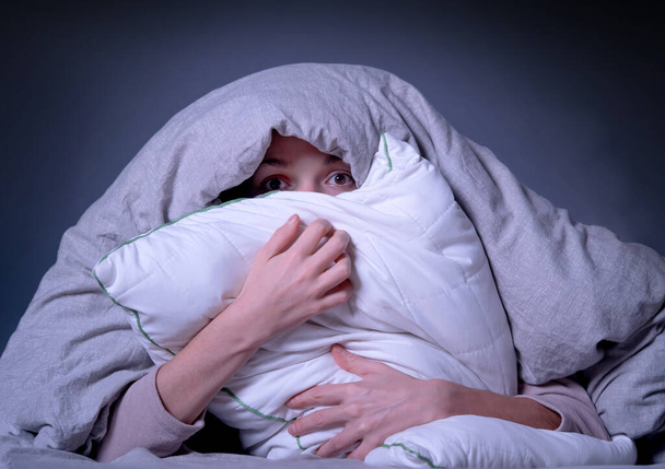 Mulher coberta com um cobertor e está preocupada com a insônia, ficando estressada. - Foto, Imagem