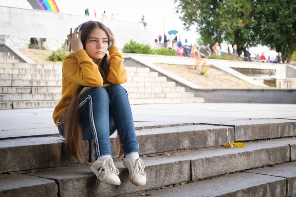 Surullinen teini tyttö istuu portaissa ja peittää päänsä käsillään - Valokuva, kuva