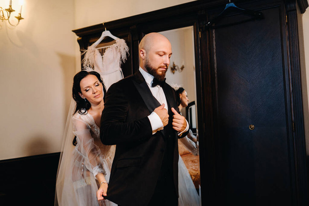 The bride in boudoir underwear dresses the groom in the interior of the hotel. - Valokuva, kuva