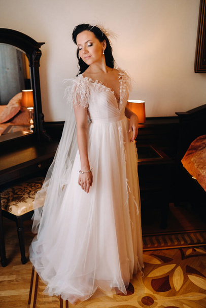 Portrait of the Bride in a wedding dress in the interior of the house near the mirror. - Photo, image