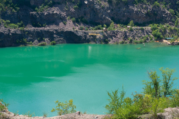 Colorful background of emerald green water saturated with radon. Flooded granite quarry. - Photo, Image