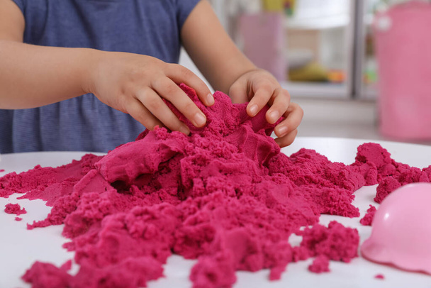 Little girl playing with bright kinetic sand at table indoors, closeup - Φωτογραφία, εικόνα