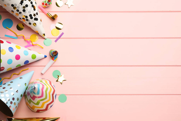 Плоская композиция на светло-розовом деревянном фоне с партийными лючками, цветочками и конфетти. Пространство для текста - Фото, изображение