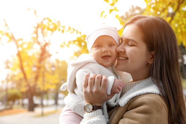 Happy mother with her baby daughter in park on autumn day, space for text - Фото, изображение
