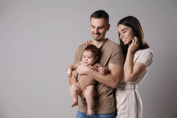Happy family. Couple with their cute baby on grey background, space for text - Foto, Bild