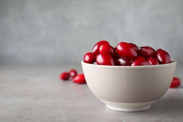 Fresh ripe dogwood berries in bowl on light grey table. Space for text - Фото, зображення